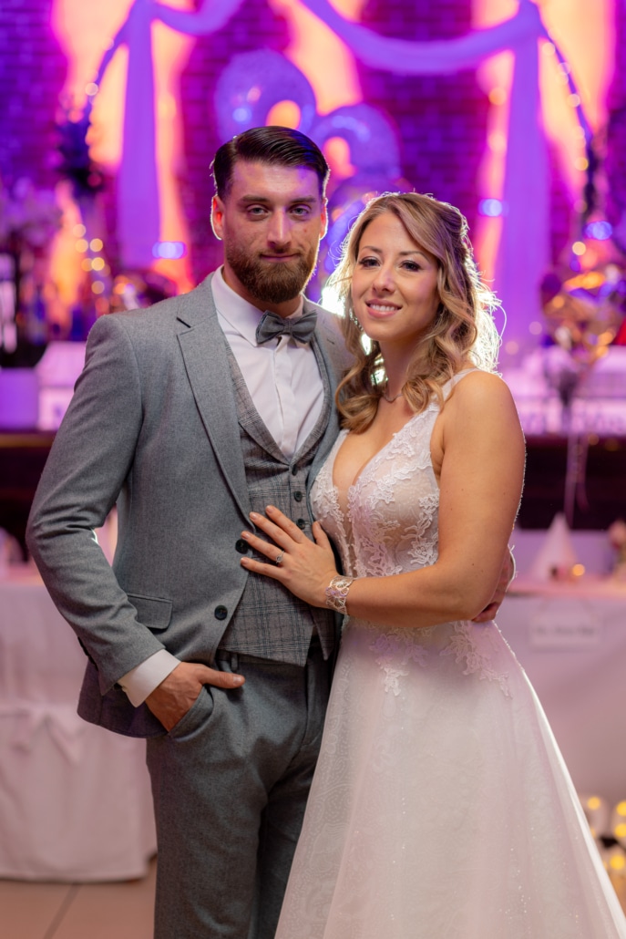 Brautpaar in festlicher Hochzeitskleidung bei einer stimmungsvoll beleuchteten Hochzeitsfeier mit elegantem Ambiente.