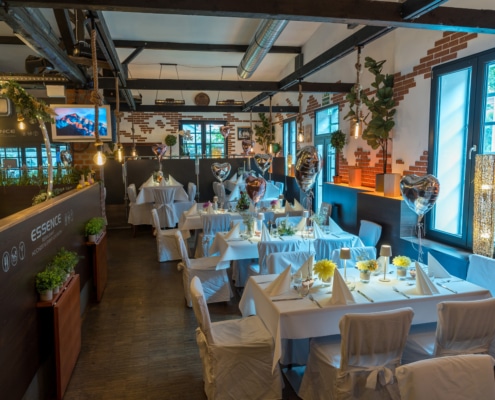 Festlich eingedeckter Hochzeitssaal im Restaurant Essence in Hagen mit weiß dekorierten Tischen, Herzballons und stilvoller Beleuchtung.