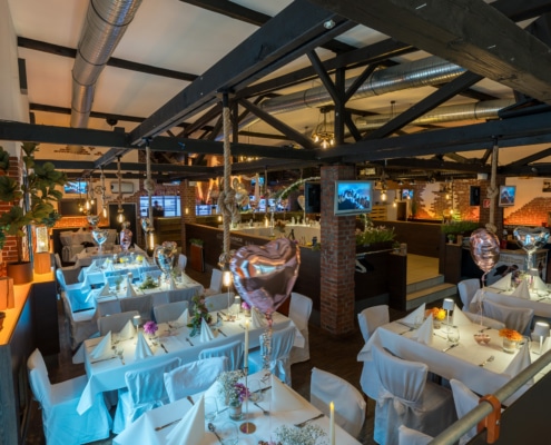 Panoramablick auf den modern-rustikalen Hochzeitssaal im Restaurant Essence in Hagen mit liebevoll dekorierten Tischen und festlicher Atmosphäre.