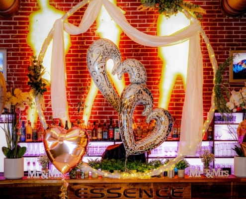 Romantische Hochzeitsdekoration mit beleuchtetem Traubogen, Herzballons und stilvoll geschmückter Bar im Restaurant Essence.