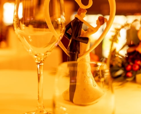Romantische Hochzeitstischdekoration mit Brautpaar-Figur im Herz, Sektglas und stimmungsvoller Beleuchtung im Restaurant Essence.