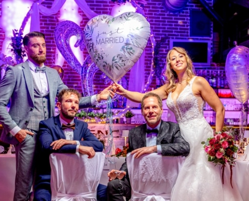Brautpaar mit Trauzeugen vor der festlich dekorierten Bar und „Just Married“-Ballon während einer Hochzeitsfeier im Restaurant Essence.